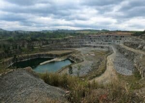 A large open-pit quarry, with visible terraces and a body of water at the bottom.