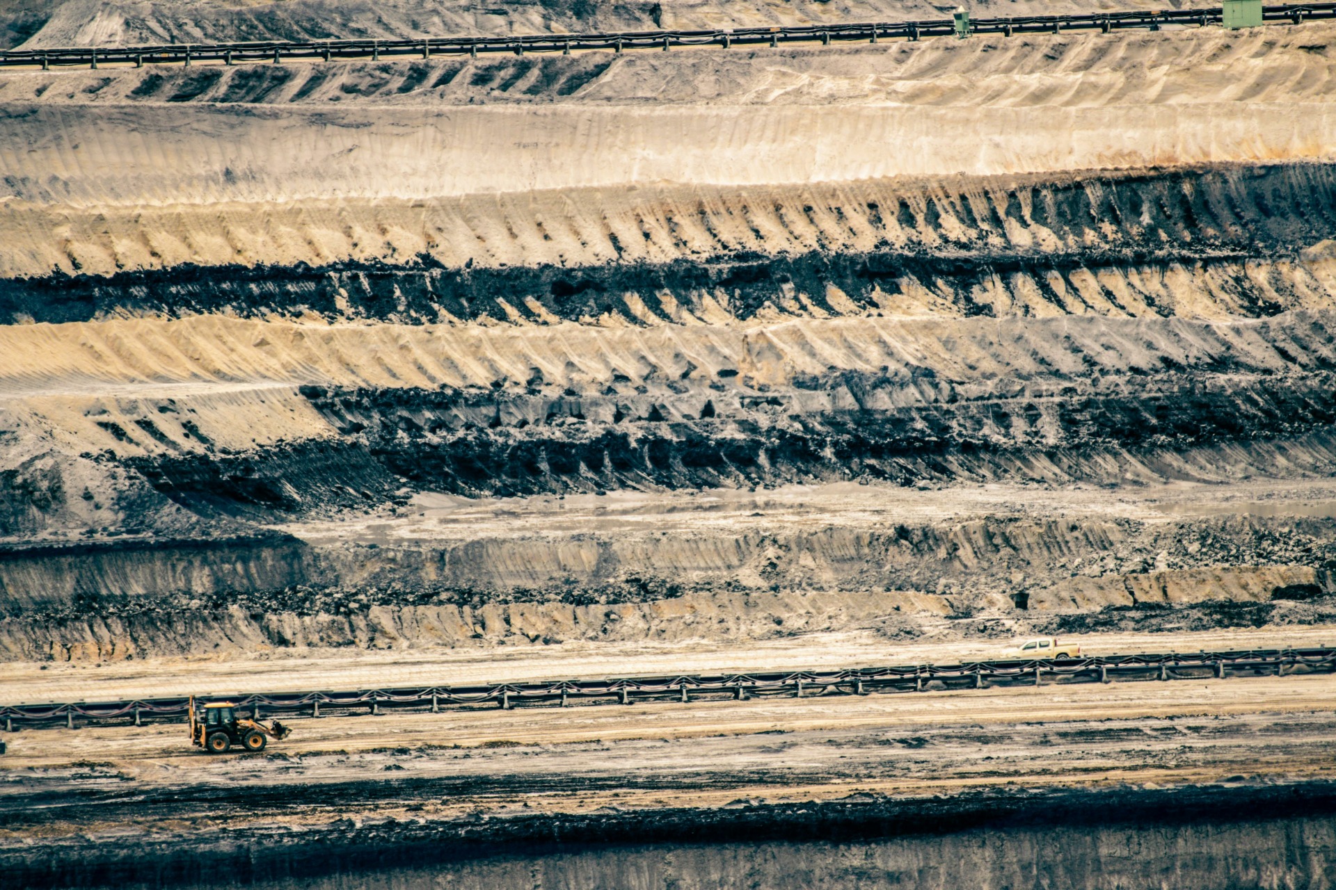 Aerial view of open-pit mine benches with excavator and haul truck on access road