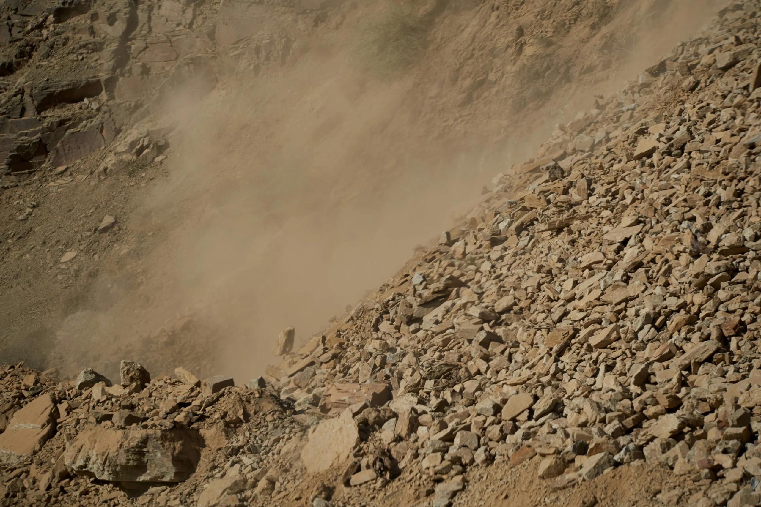 Post-blast dust cloud rising above a fragmented rock bench at Mine A, South Africa
