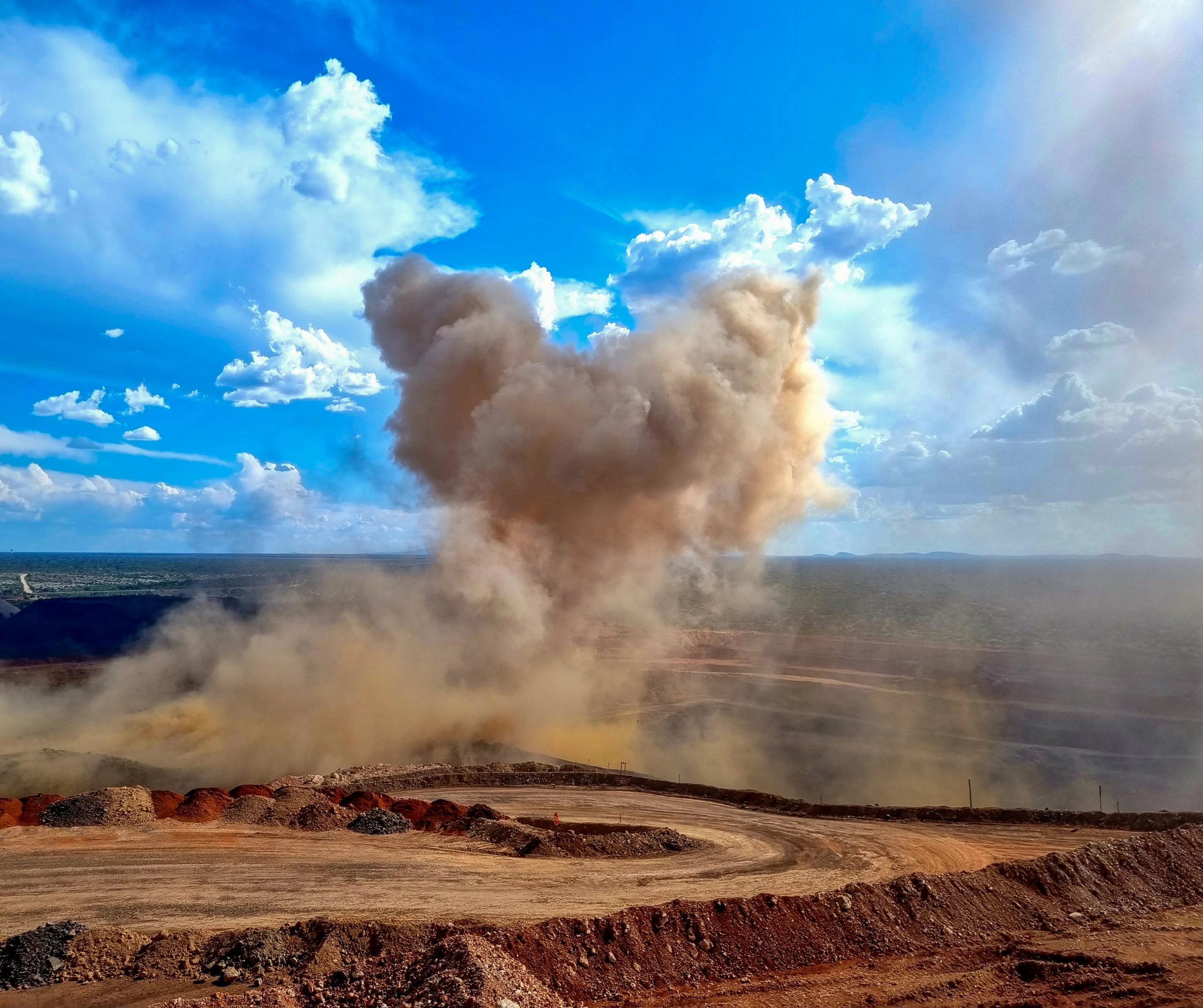 Articles 1 Open-pit bench blast throwing a large dust plume into the air — the kind of energy venting stemming plugs help confine.